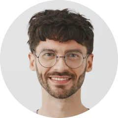 A man with glasses and a beard smiling.